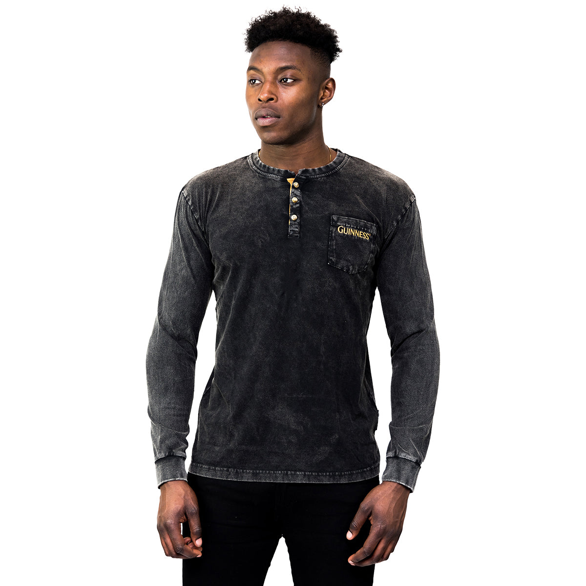 A man faces forward wearing a faded black Guinness Classic Henley long sleeve shirt with collar buttons and a logo on the chest pocket, set against a white background.