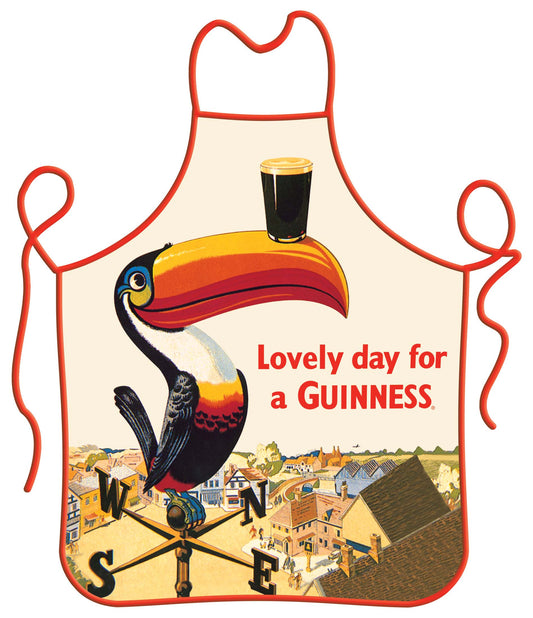 An Guinness Toucan Chef Apron featuring a vintage Guinness advertisement with a toucan balancing a pint of beer on its beak, above an illustrated town scene, and the text "lovely day for a Guinness.
