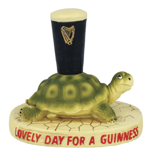 A Guinness Gilroy Tortoise Figurine wearing a Guinness UK hat perched atop it.