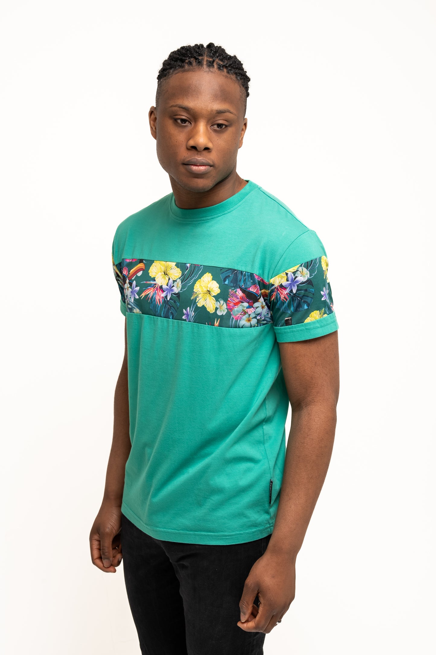 A man wearing the Guinness Toucan Hawaiian Green T-Shirt by Guinness UK and black pants stands against a plain white background.