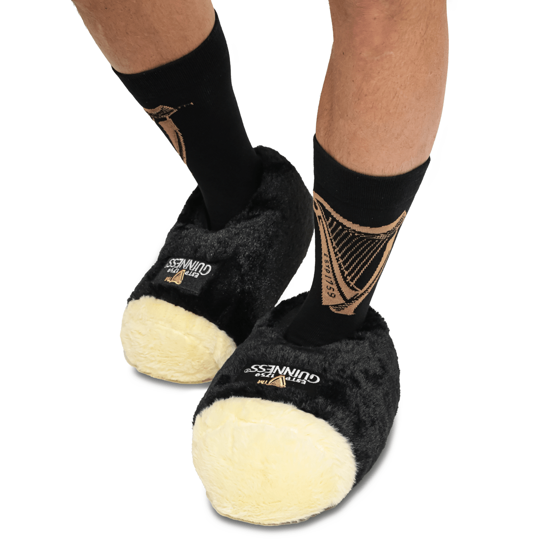 A man wearing a pair of black and gold Guinness Pint slippers.