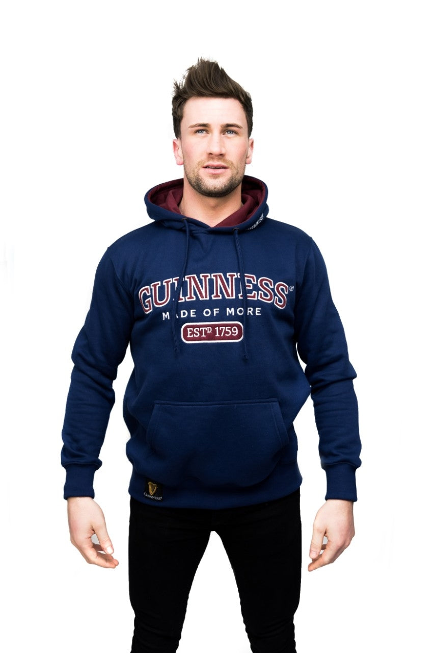 A man wearing a navy Guinness UK hoodie with a hood and a red and white logo.