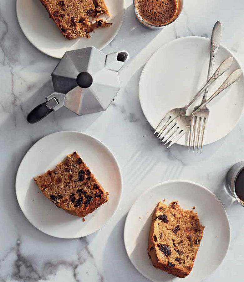 A slice of cake on a plate next to a cup of coffee, perfect for the Official Guinness Hardcover Cookbook by Guinness UK.