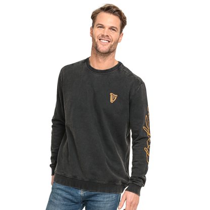 A man wearing a Guinness Harp Sweatshirt - Black Distressed Gold by Guinness UK and jeans.