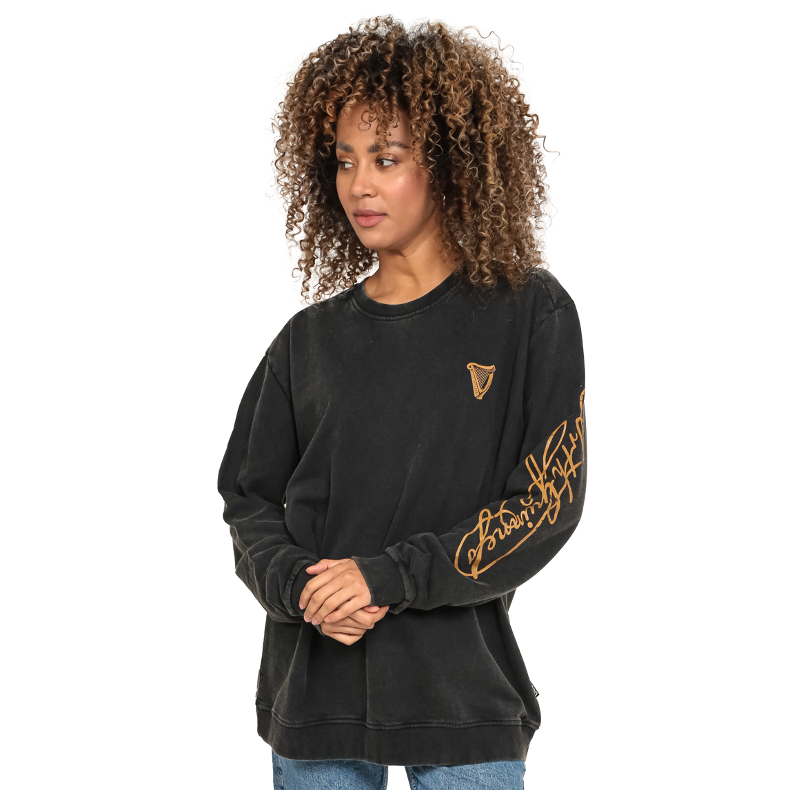 A woman wearing a cozy Guinness Harp Sweatshirt - Black Distressed Gold by Guinness UK with gold lettering.
