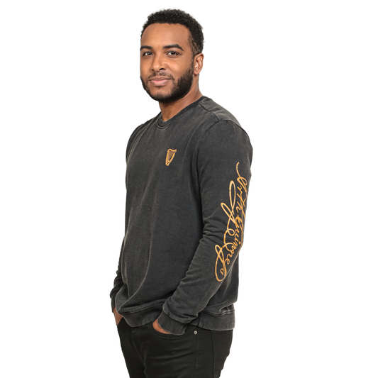 A man wearing a cozy Guinness Harp Sweatshirt - Black Distressed Gold with gold lettering.