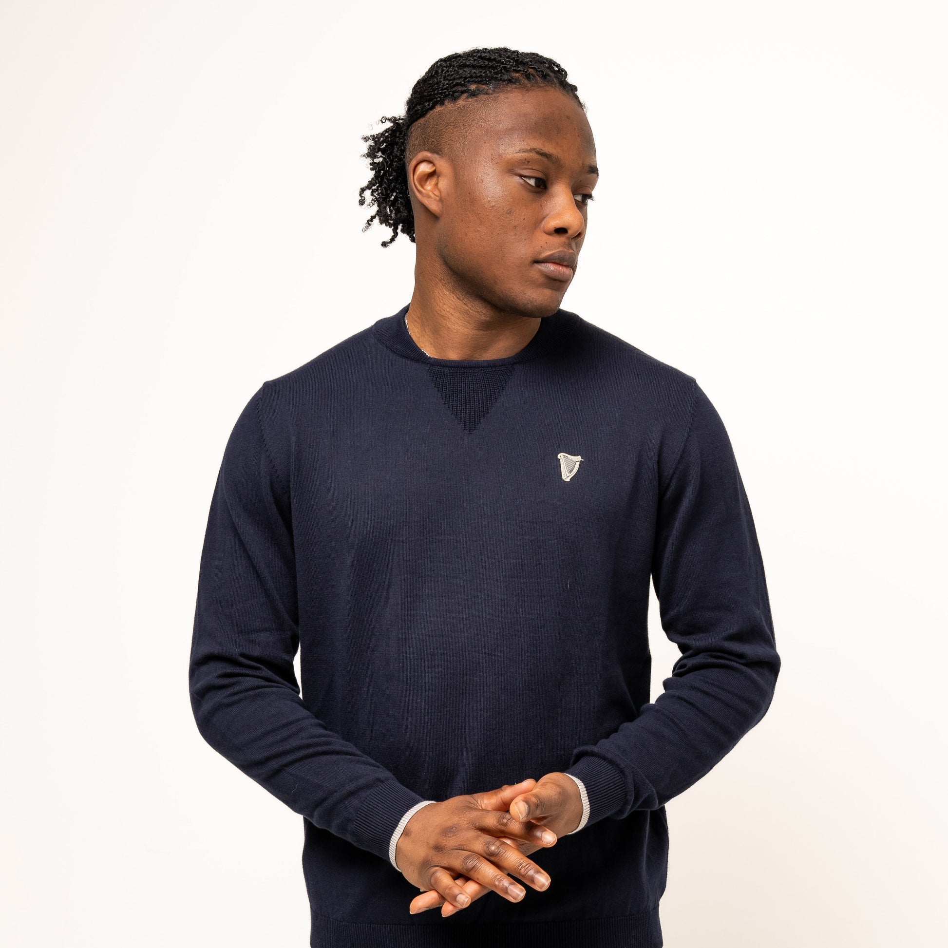 A person stands against a white background, wearing the Guinness Webstore UK's Performance Cotton Sweater in navy—crafted from moisture-wicking cotton—plus matching navy shorts, ideal for stylish comfort both on and off the golf course.