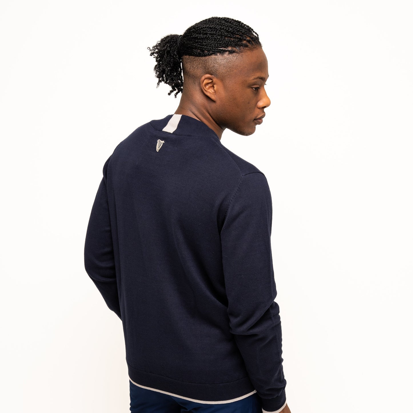 A man in the Guinness Webstore UK Performance Cotton Sweater - Navy and navy shorts stands turned to the side against a white background—ideal for the golf course with its moisture-wicking cotton fabric.