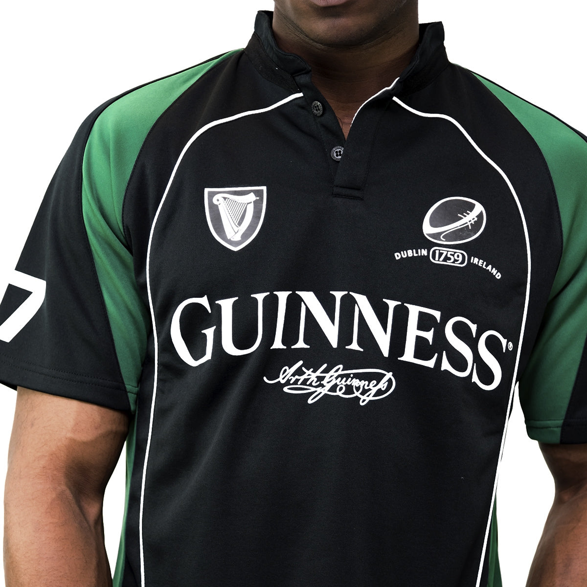 A man wearing a Guinness UK Black and Green Short sleeve performance Rugby Jersey.