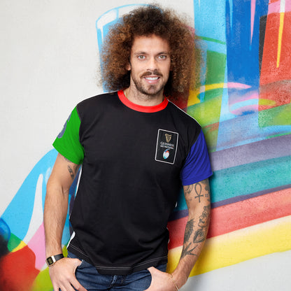 A man with curly hair standing in front of a colorful wall, wearing a Guinness UK Six Nations Premium Colour Block T-Shirt.