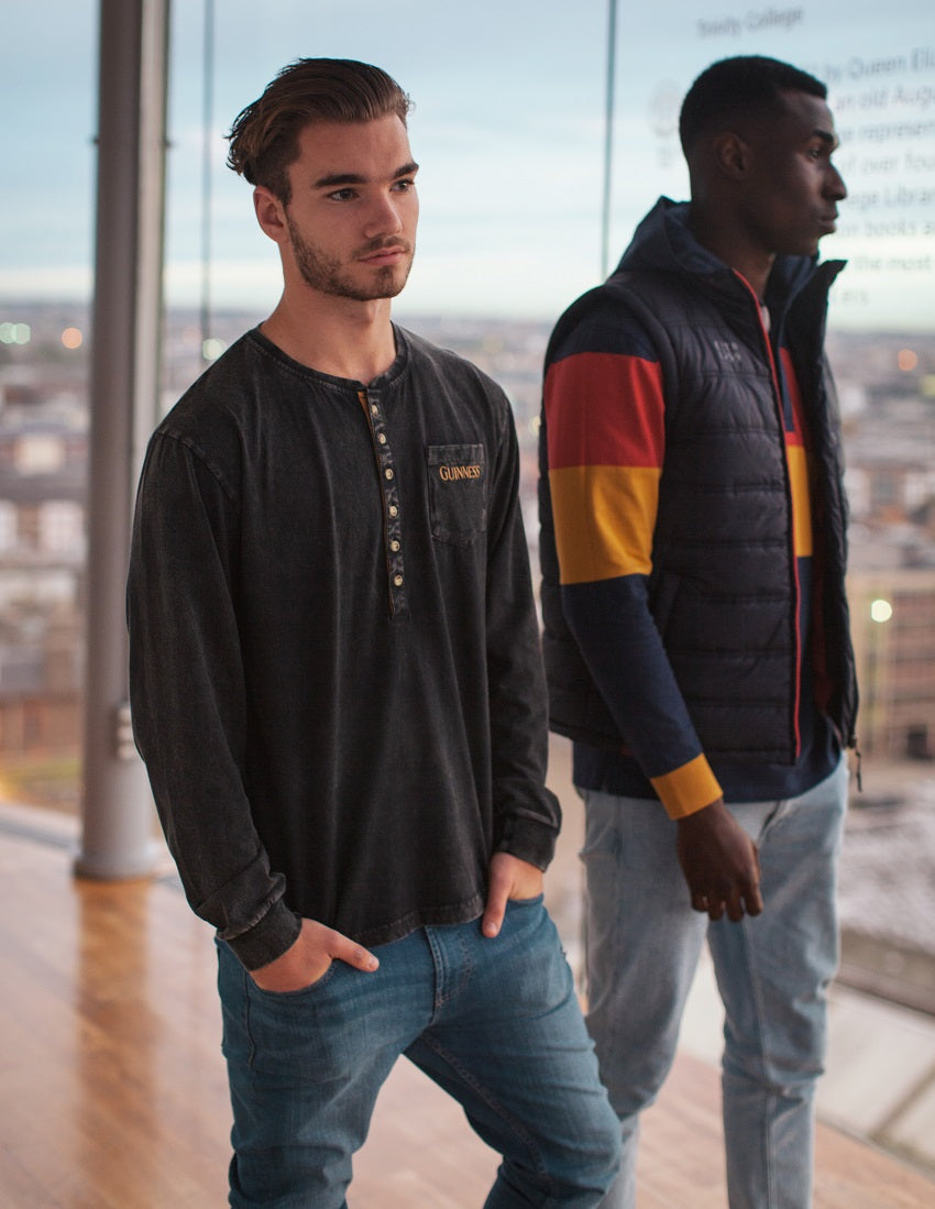 Two men wearing Guinness Hooded Rugby Jerseys standing next to each other in front of a window.