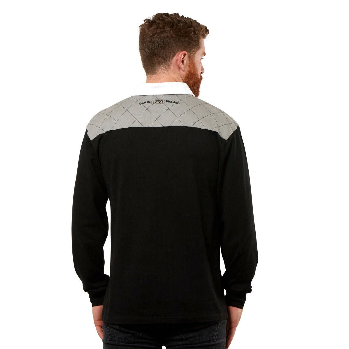 The back view of a man wearing a Guinness Heritage Charcoal Grey and Black Long Sleeve Rugby Jersey made by Guinness UK, in 100% cotton material.