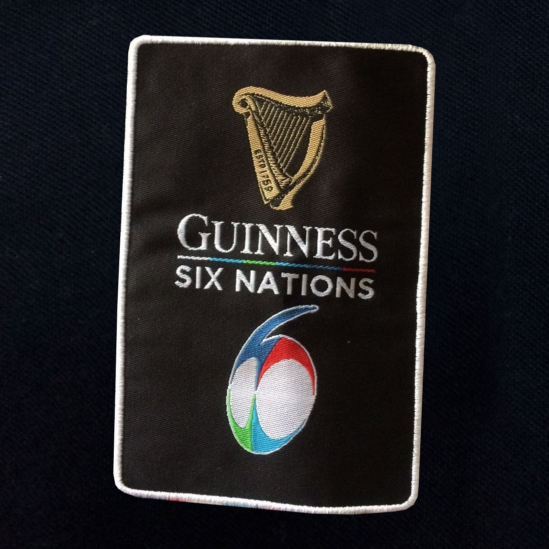 The Guinness Six Nations Black Polo is displayed on a black background.