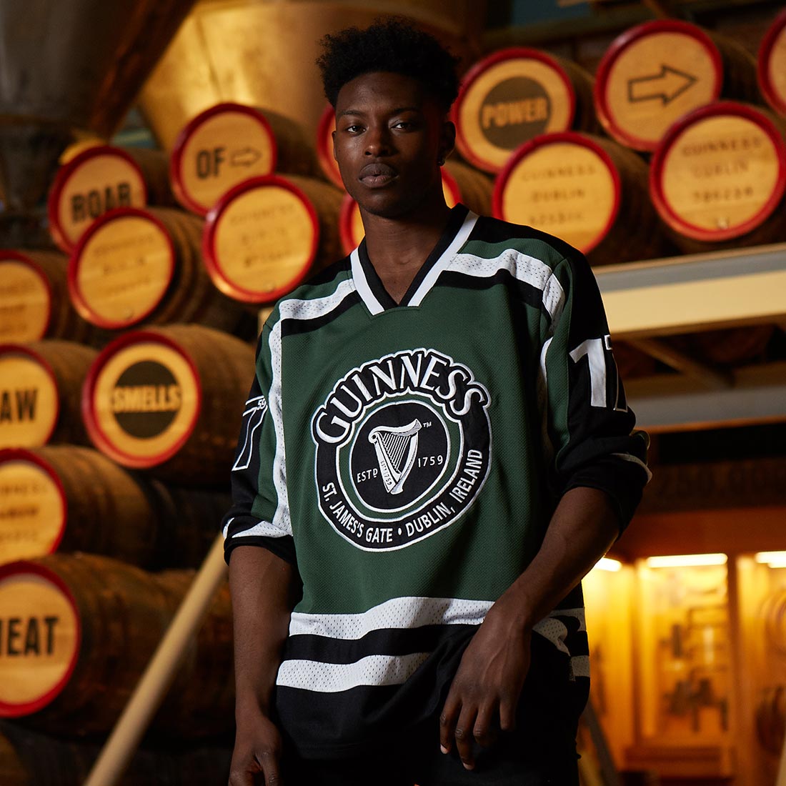 A young man sporting a green and black Guinness UK HARP Hockey Jersey made of polyester.