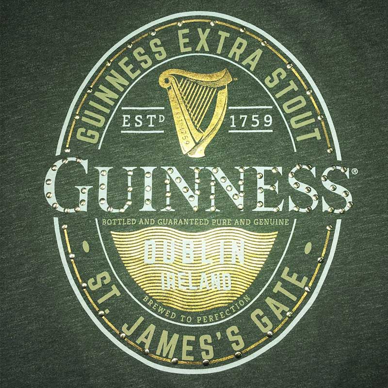 Guinness Stud Label T-shirt design featuring the logo of Guinness Extra Stout with text, harp emblem, and establishment details on a grey background.