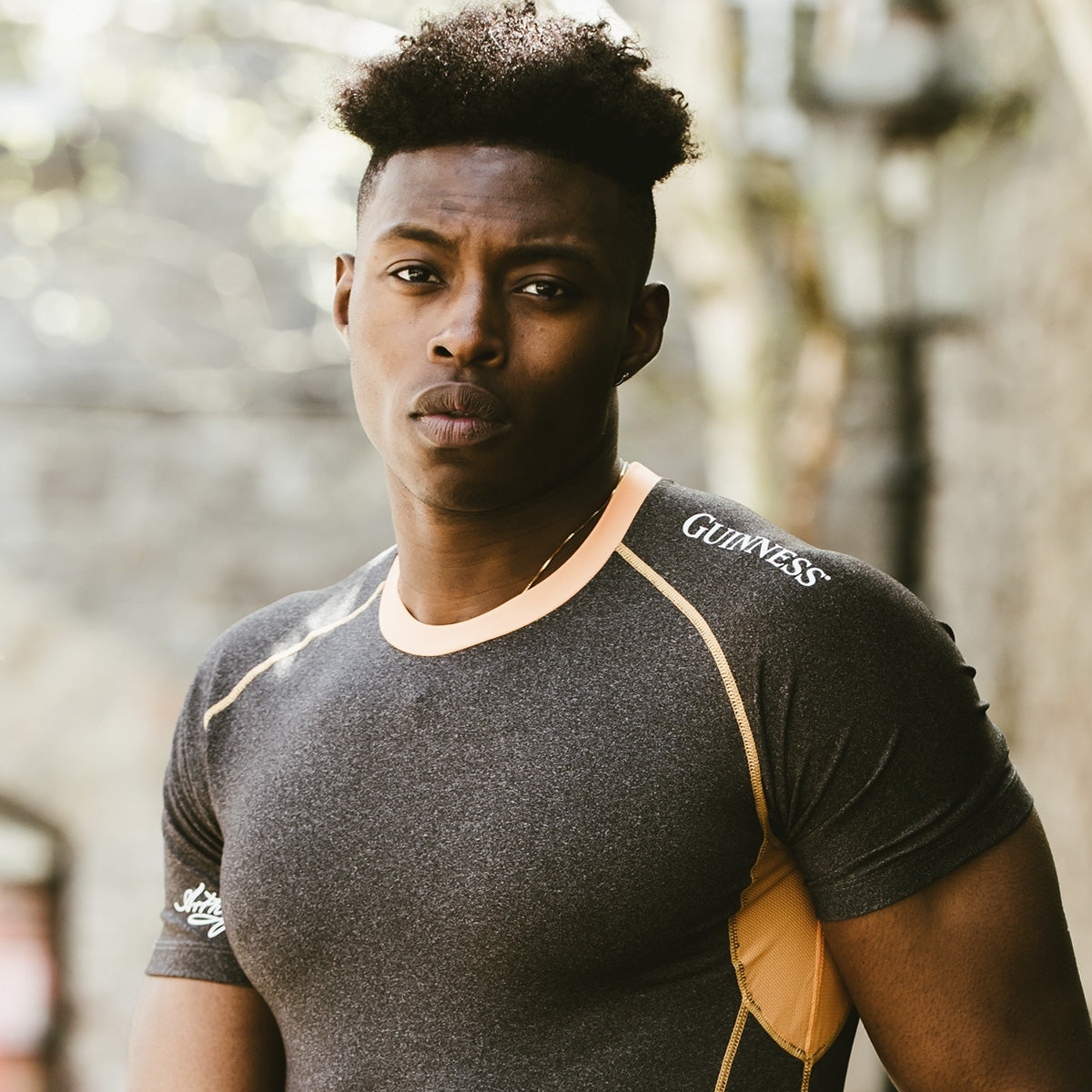 A black man wearing a grey Guinness UK t-shirt.