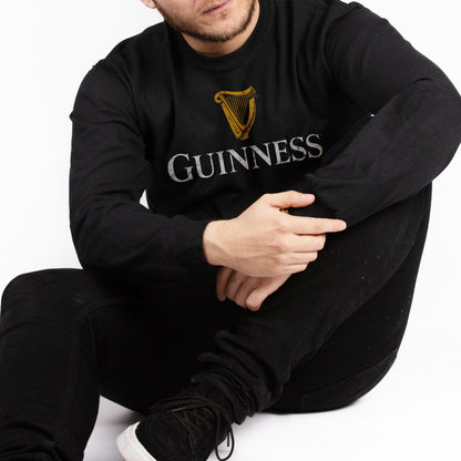 A man wearing a Guinness UK Guinness Black Trademark Label Long Sleeve T-Shirt.