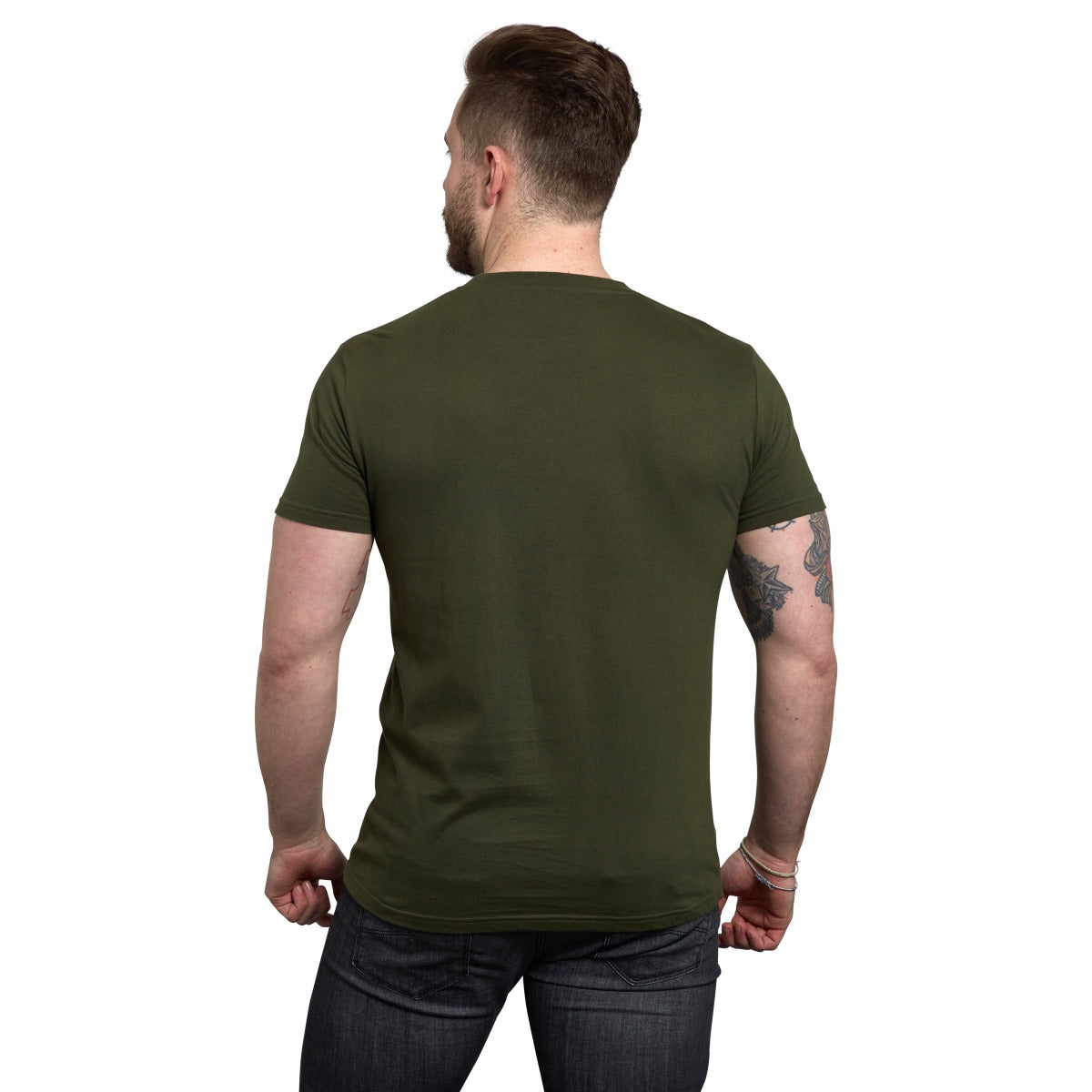 A man with short hair, seen from behind, wears a Guinness UK Khaki Green Gaelic Label Tee and dark jeans, standing against a white background.