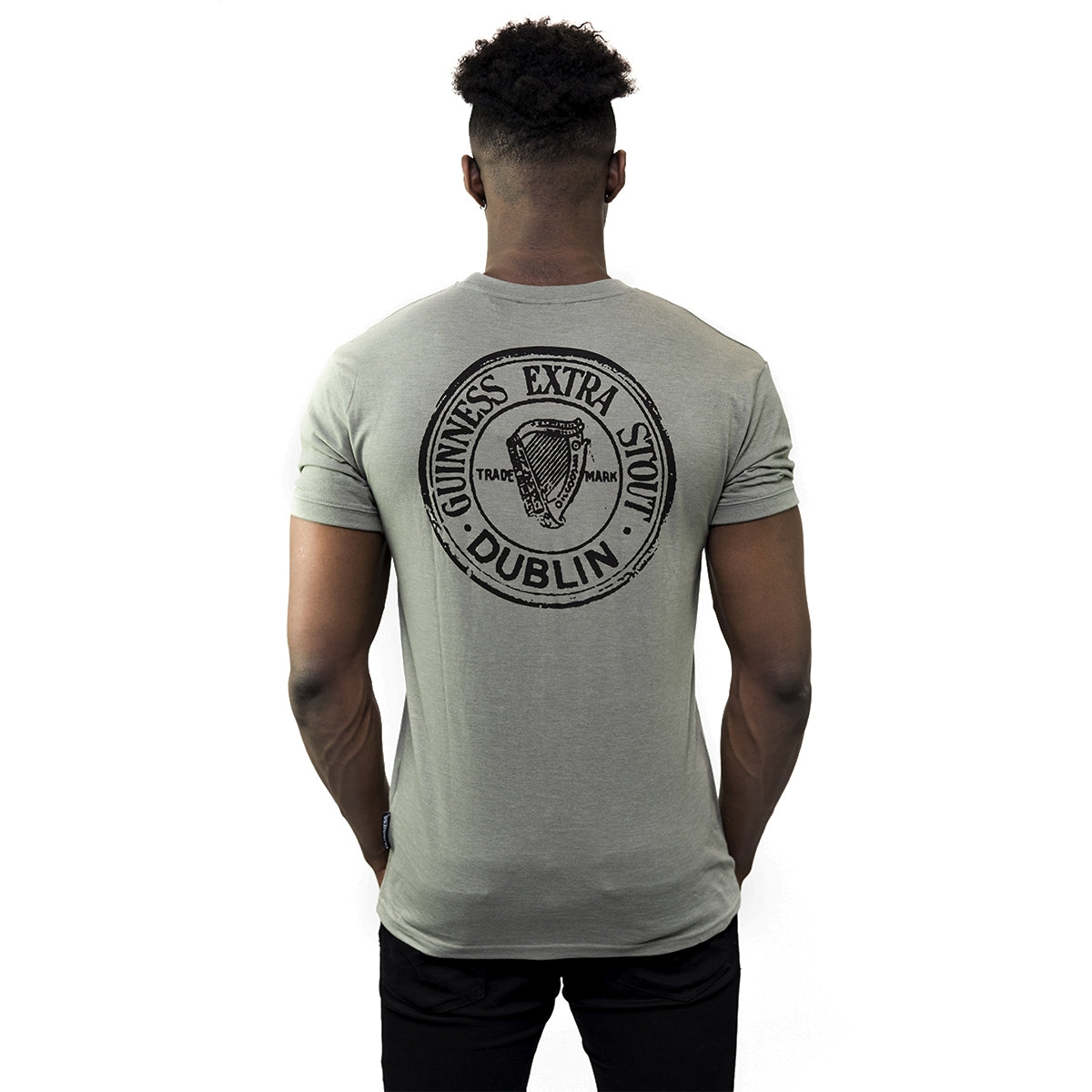The man's back is visible as he wears a Guinness Green Heathered Bottle Cap T-Shirt made from a cotton blend fabric.