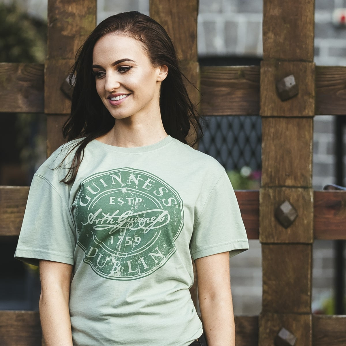 A young woman wearing a Guinness Green Bottle Cap T-Shirt.