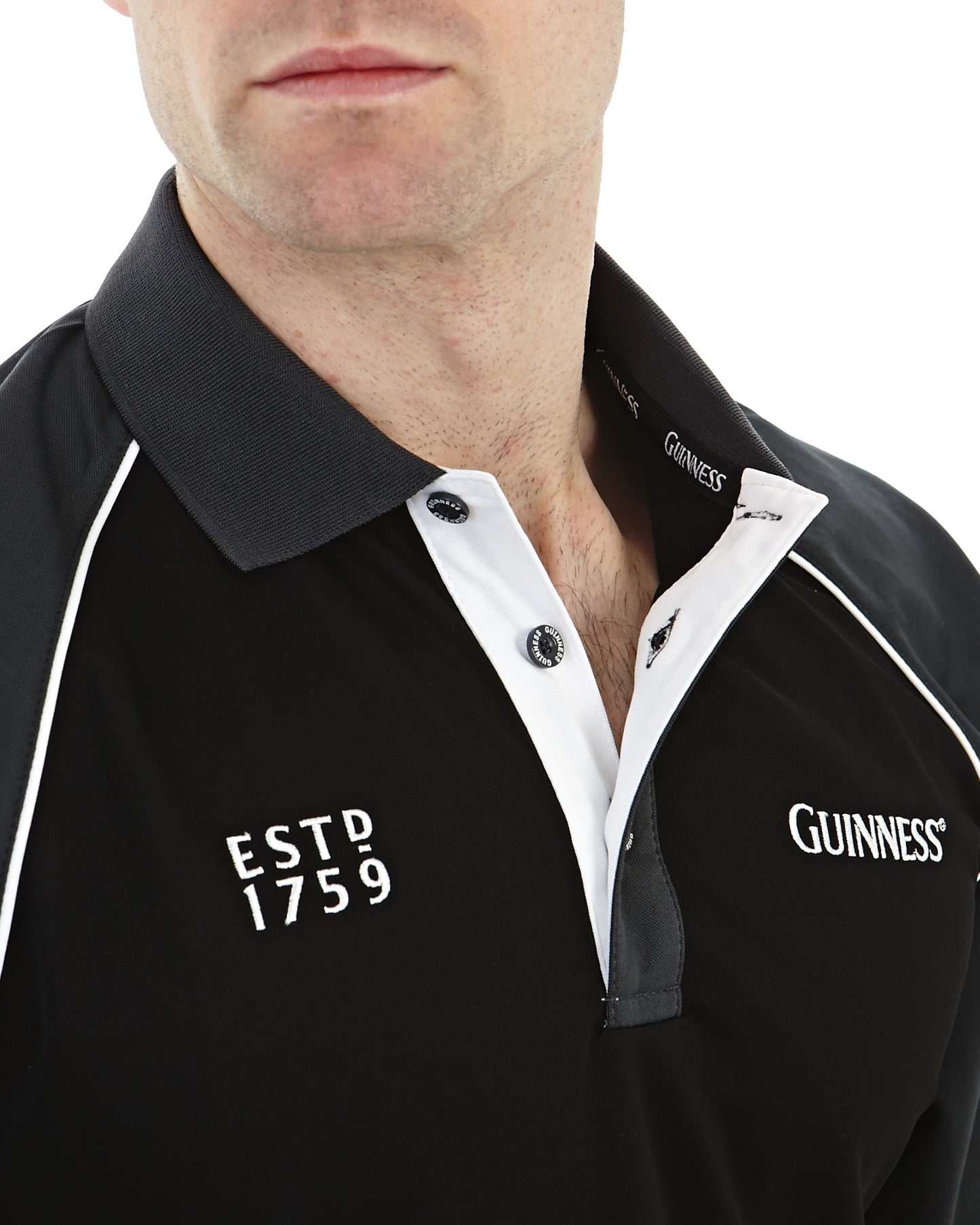 A close-up of a person wearing the Guinness Golf Shirt from Guinness. The black and white performance polo shirt showcases "ESTD 1759" and "GUINNESS" embroidered on the chest, and is made from moisture-wicking fabric for enhanced comfort.