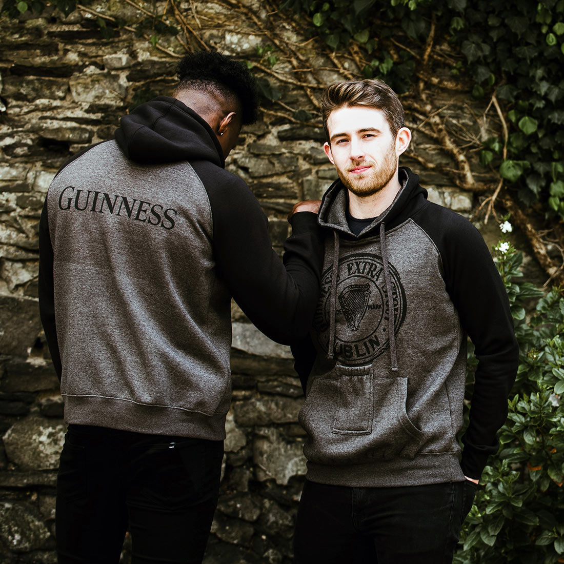 Two men standing next to each other wearing matching Guinness Hoodies with Bottle Pockets.