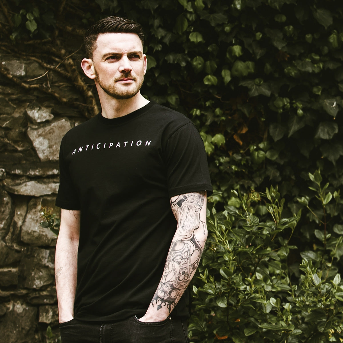 A man wearing a distressed Guinness Vintage Turtle Back Graphic T-Shirt with tattoos, featuring a Turtle Back Graphic.