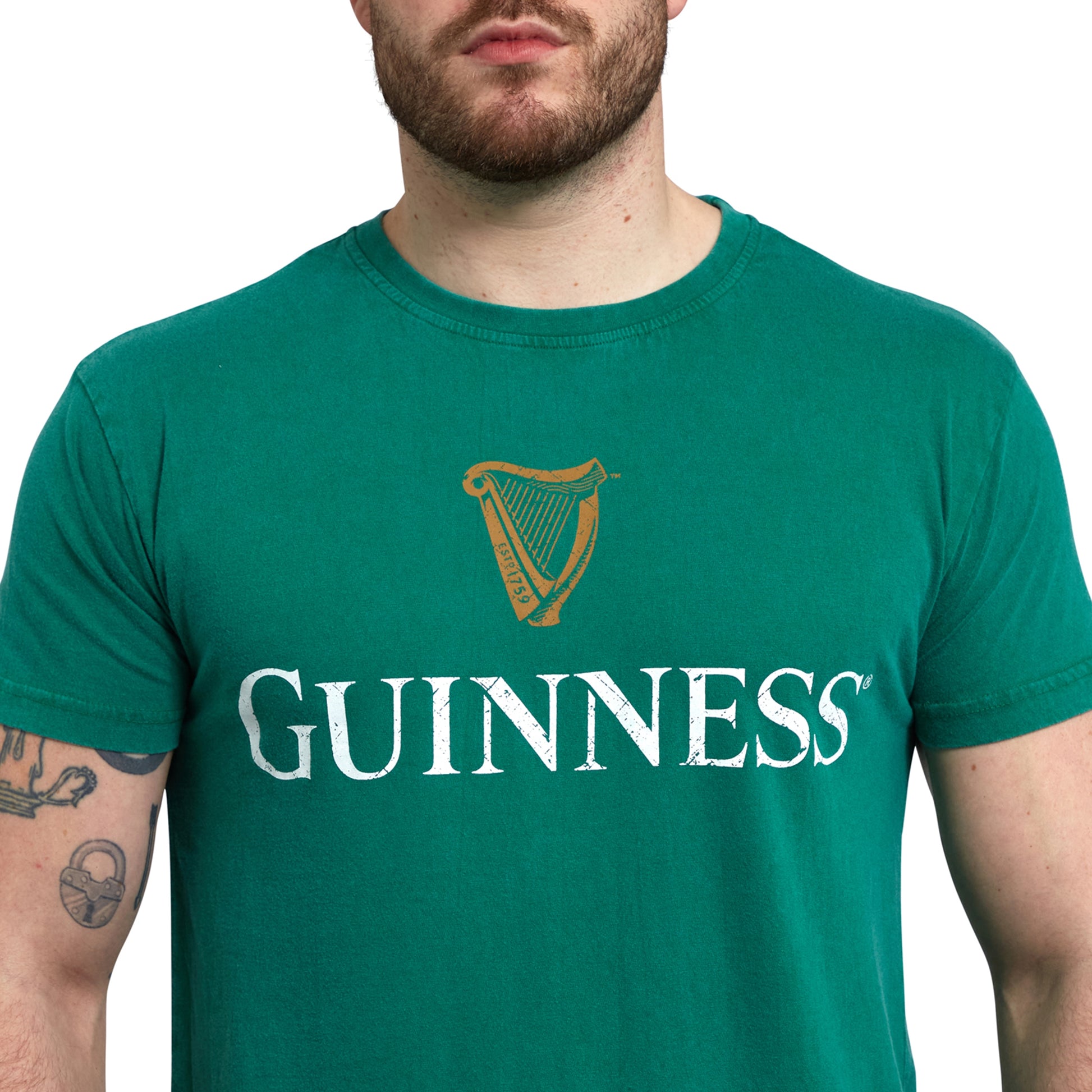 A man wearing a Green Guinness Harp Premium T-Shirt, showcasing the iconic Harp symbol, representing Ireland and produced by Guinness UK.