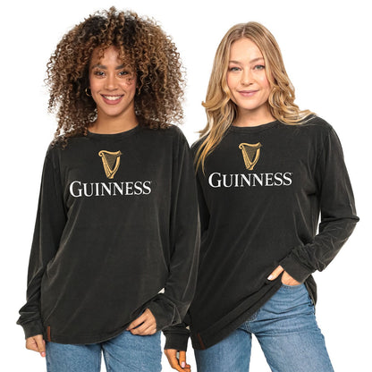 Two women smiling and standing side by side, wearing black Guinness® Premium Harp Jumpers and jeans.