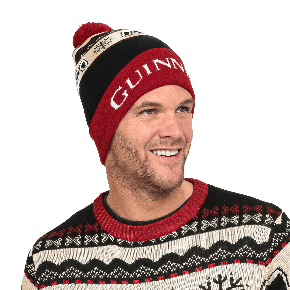 A man wearing an ugly sweater with a Guinness UK logo and snowflakes on it, paired with an Official Pint Winter Beanie.