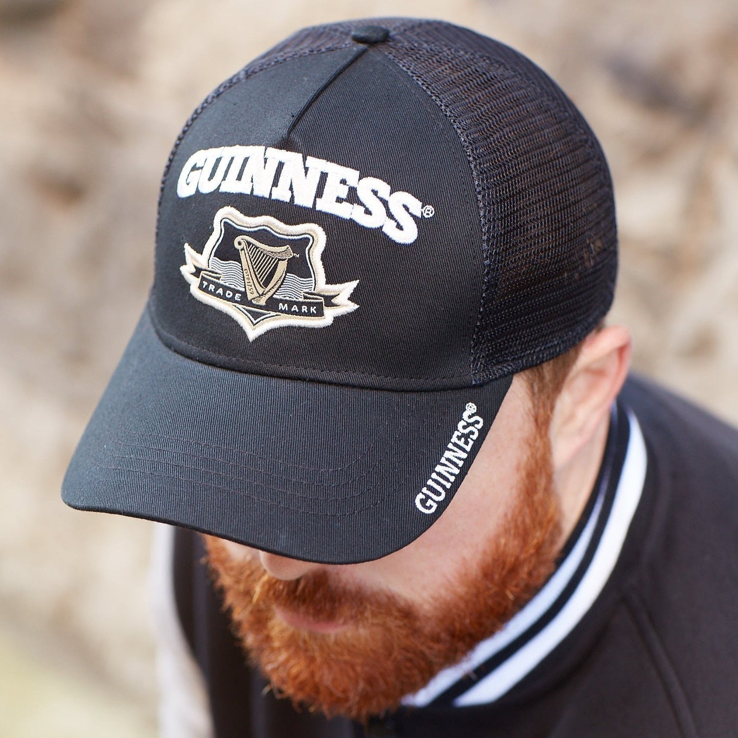 A man with a beard wearing a Guinness UK Black Trucker Baseball Cap.