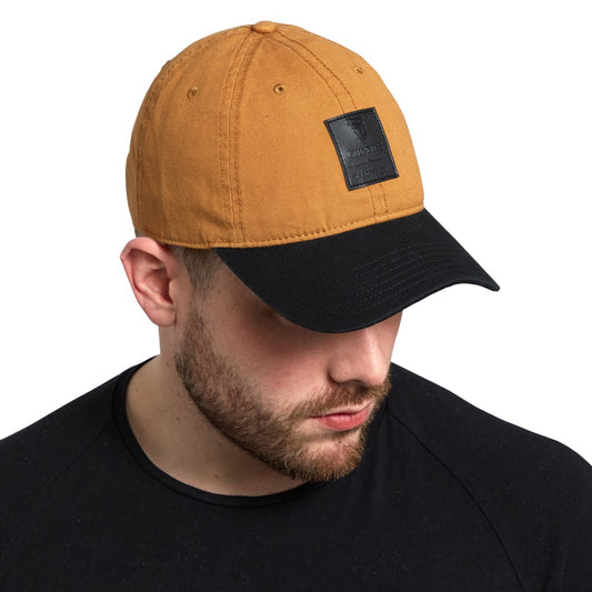 A man wearing a Guinness UK adjustable size brown and black Guinness Premium Camel & Black with Black Leather Patch baseball cap.