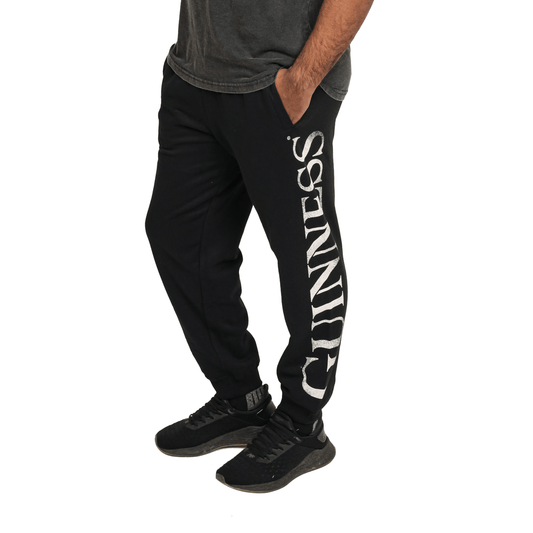 A man wearing Guinness UK joggers with the word Guinness on them.