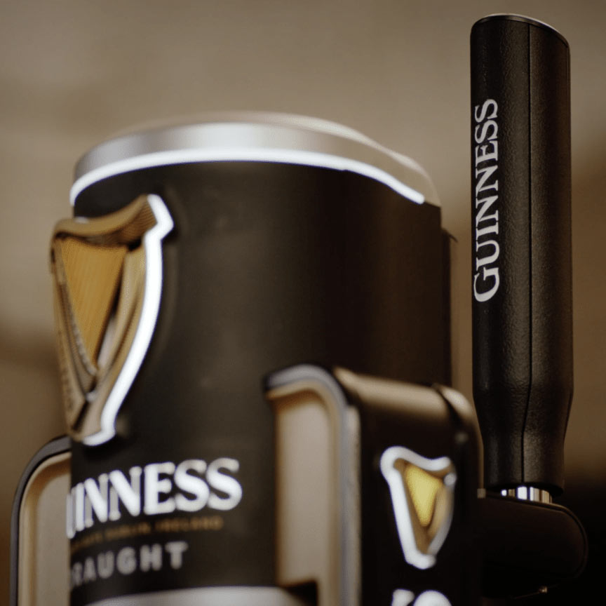 A Guinness UK MicroDraught beer tap with a black handle.
