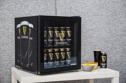 A Guinness beer fridge sitting on a table, keeping brews chilled.