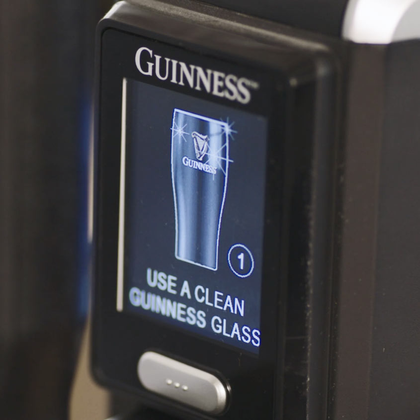 A machine screen displaying a message with an image of a Guinness glass that reads "USE A CLEAN GUINNESS® GLASS" for your home bar, perfect for pouring Guinness MicroDraught from your Guinness UK.