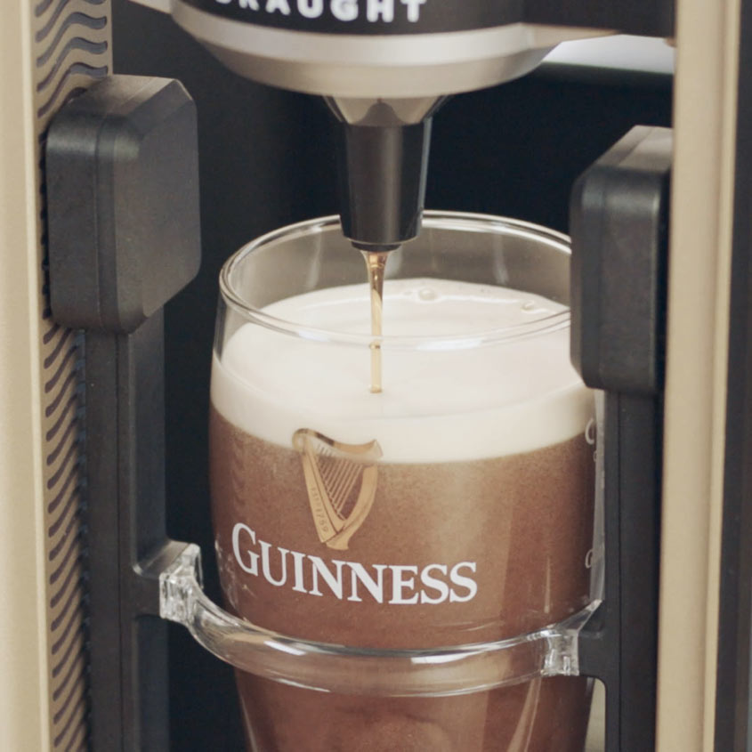 The Guinness UK MicroDraught machine is being used to make a drink at a home bar.