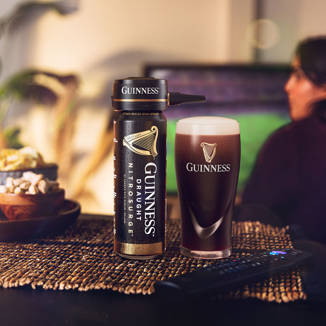 A bottle of Guinness Nitrosurge Unit next to a glass of beer, showcasing the pouring experience and mesmerizing nitrogen bubbles.