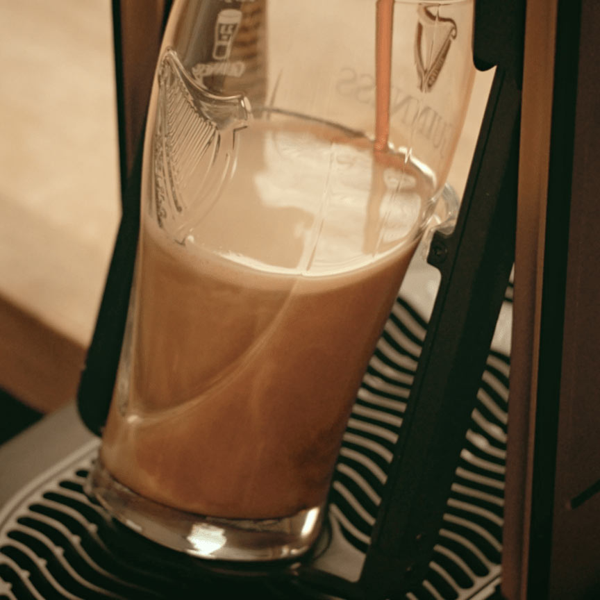 A Guinness UK MicroDraught is being poured into a glass at a home bar.