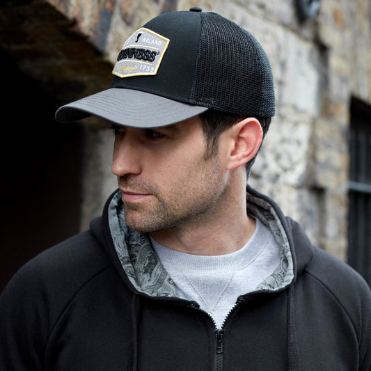 A man wearing a Guinness UK Guinness Trucker Premium Grey with Embroidered Patch Cap.