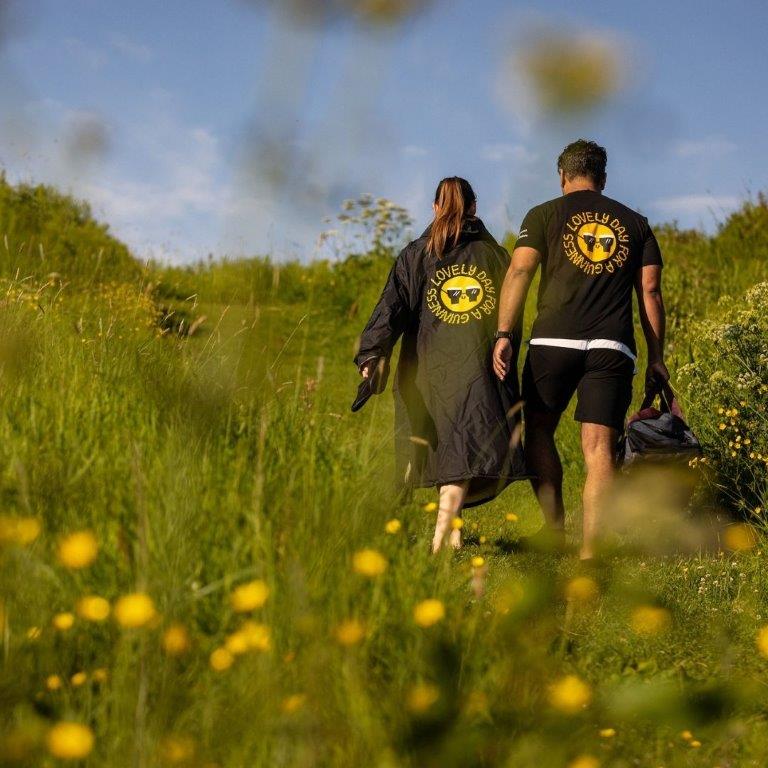 A man and woman walking through a Guinness Webstore UK collection of FATTI BURKE "LOVELY DAY FOR A GUINNESS" BLACK T-SHIRTS.