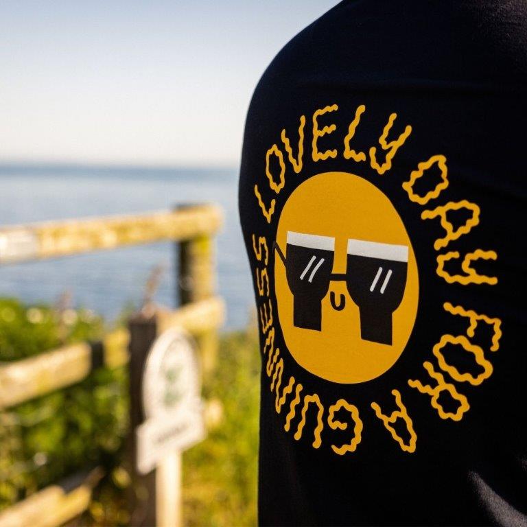 A man wearing a FATTI BURKE "LOVELY DAY FOR A GUINNESS" BLACK T-SHIRT from the Guinness Webstore UK festival season.