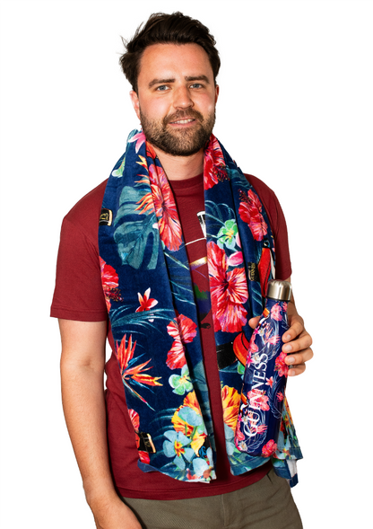 A man wearing a reusable Guinness Toucan Hawaiian print scarf, holding a Guinness stainless steel water bottle.