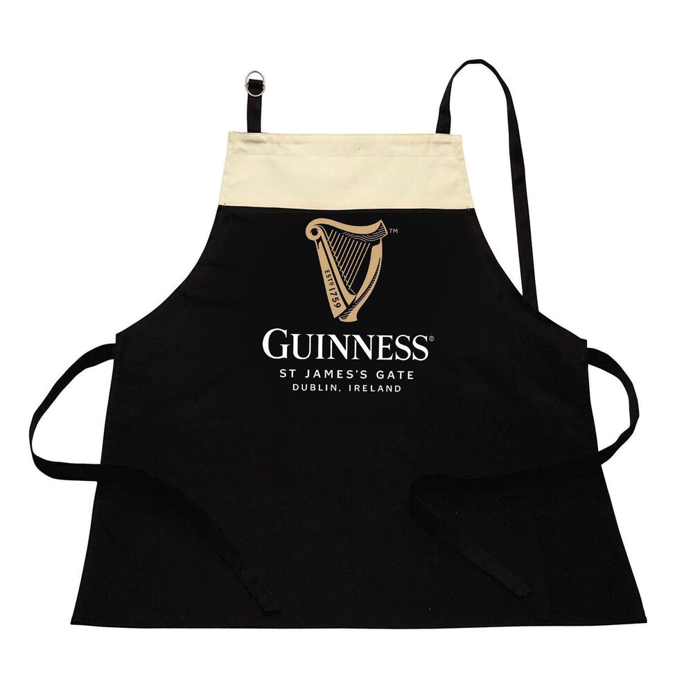 The Guinness Pint Apron, a stylish kitchen accessory, features a black design with a beige upper section displaying the iconic Guinness logo and harp design. Crafted from 100% cotton, it includes the text "St James's Gate, Dublin, Ireland" beneath the logo, blending tradition with modern style.