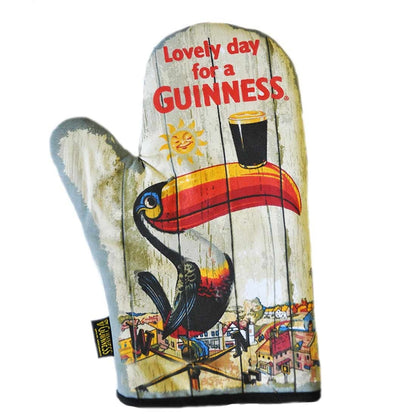 The Guinness UK vintage decor kitchen oven mitt, known as the "Guinness Toucan Oven Glove," features the iconic Gilroy Toucan with a beer glass on its bill. This charming mitt displays the text "Lovely day for a GUINNESS" on a wooden plank background, making it an ideal addition to any Guinness novelty collection.