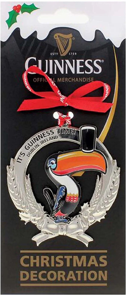 This festive Guinness Metal Decoration - Toucan, from the Gilroy Collection, features a charming toucan perched on a silver wreath. It includes a red ribbon with the phrases "It's Guinness Time" and "Dublin, Ireland," making it a delightful addition to your holiday decor.