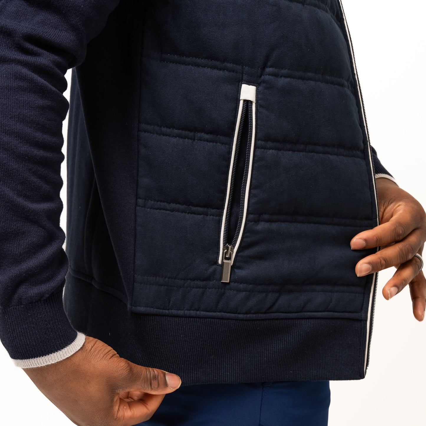 A person stands sideways wearing the Guinness Webstore UK Guinness Performance Gilet with quilted details and navy shorts, one hand near the gilet’s zippered pocket.