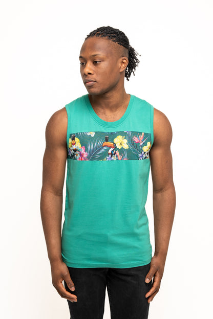 A man in the Guinness Toucan Hawaiian Green Tank from Guinness Webstore UK, featuring a floral and toucan chest design, stands slightly turned against a plain white background, channeling true tropical paradise vibes.