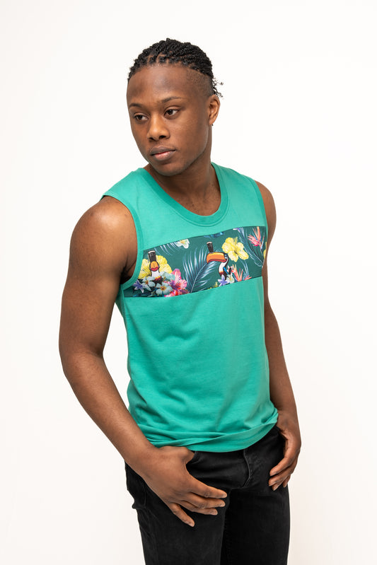 A man stands against a plain white background wearing the Guinness Webstore UK Guinness Toucan Hawaiian Green Tank, which features a vibrant floral and toucan design that radiates tropical paradise vibes.