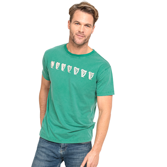 A man wearing a green Guinness Evolution Harp Green T-shirt and jeans.